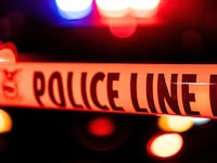 Police tape in front of flashing police lights.