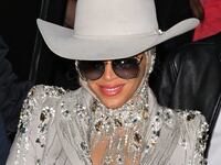 Beyoncé smiles while wearing a cowboy hat.