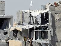 Fighters of Syrian Democratic Forces raise a white flag near the National Hospital complex where the Islamic State militants are holed up, at the frontline in Raqqa, Syria October 16, 2017.
