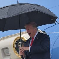 US President Donald Trump shelters from the rain under an umbrella as he disembarks from Airforce One in Los Angeles, California on March 13, 2018. (Photo by MANDEL NGAN / AFP) (Photo by MANDEL NGAN/AFP via Getty Images)