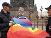 Policemen talk to a gay rights activist holding a rainbow flag during a protest in Dvortsovaya Square in St. Petersburg, Russia, Aug. 2, 2015.