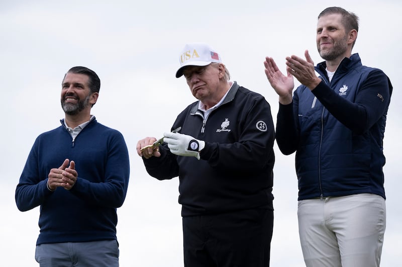 US President Donald Trump (C), flanked by his sons Eric Trump (R) and Donald Trump Jr. (L) cuts the ribbon on the first tee to officially open the Trump International Golf Links course in Balmedie, Aberdeenshire, north east Scotland on July 29, 2025. (Photo by Brendan Smialowski / AFP) (Photo by BRENDAN SMIALOWSKI/AFP via Getty Images)