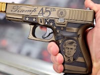 A worker shows off Glock 19 Donald Trump commemorative 9mm pistol being offered for sale at Freddie Bear Sports on April 08, 2021 in Tinley Park, Illinois.