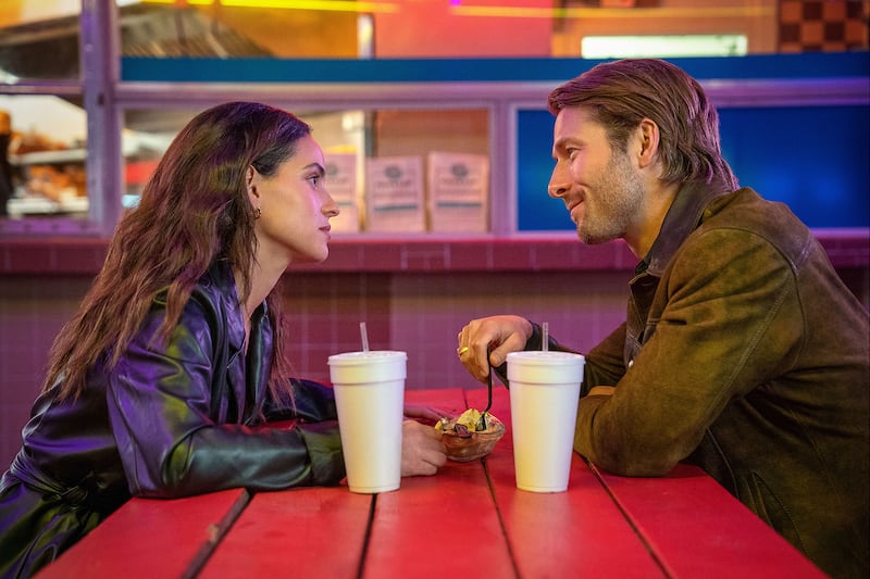 Adria Arjona and Glen Powell sit at a table in 'Hit Man'