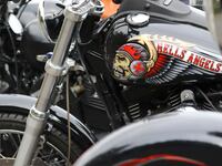 A parked Harley-Davidson motorcycle with a Hells Angels logo and a fierce-looking skull painted on the gas tank.