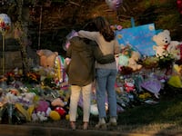 Community members embrace while visiting a memorial at the school entrance after a deadly shooting at the Covenant School in Nashville, Tennessee, March 29, 2023.