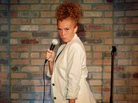 Michelle Wolf stands with a microphone on stage