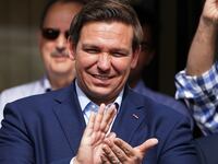Ron DeSantis smiles and claps