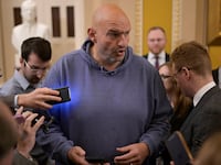 John Fetterman, wearing a blue hoodie on Capitol Hill, speaks with reporters.