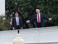 U.S. President Donald Trump gestures while answering questions from reporters as he tours the roof of the West Wing of the White House