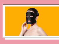 Woman wearing the Lumina LED Therapy Mask, its black. The woman is on an orange background.