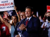 Ron DeSantis looks in awe at a Trump rally in front of a MAGA sign