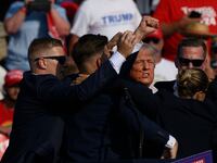 Donald Trump getting escorted off stage by Secret Service agents.