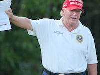 A picture of Donald Trump showing printouts of political polls to reporters during a golf tournament at his club in New Jersey.