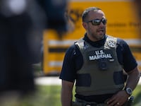 BENSENVILLE, ILLINOIS - SEPTEMBER 10: A U.S. Marshal stands guard outside Midwest Distribution during a press conference after it was raided by federal agents on September 10, 2025 in Bensenville, Illinois. According to the company, various e-liquids were seized in the raid. (Photo by Scott Olson/Getty Images)