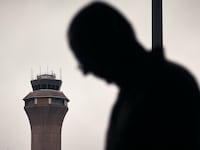 A man stands outside Terminal C with the airport control tower in the background at Newark Liberty International Airport.