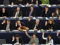 Members of the European Parliament vote with raised hands in seats.
