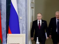 Russian President Vladimir Putin and Belarusian President Alexander Lukashenko walk through doors.