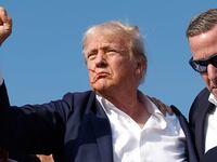 Former President Donald Trump pumps his fist as he is rushed offstage by U.S. Secret Service agents.