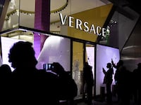 People take pictures with their mobilephones of the broken window of the Versace store after clashes following a demonstration in Barcelona on February 20, 2021.
