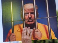 A demonstrator holds an image of US President Donald Trump behind prison bars during a protest against the Trump administration during the "No Kings" national rally in downtown Los Angeles, California, on June 14, 2025, on the same day as President Trump's military parade in Washington, DC. Tens of thousands of protesters rallied nationwide Saturday against Donald Trump ahead of a huge military parade on the US president's 79th birthday -- as the killing of a Democratic lawmaker underscored the deep divisions in American politics. "No Kings" demonstrators took to the streets in New York, Los Angeles, Chicago, Philadelphia, Houston, Atlanta and hundreds of other cities across the United States to condemn what they call Trump's dictatorial overreach. (Photo by RINGO CHIU / AFP)