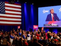 A monitor shows Donald Trump speaking at CPAC as supporters in the crowd cheer