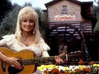 Dolly Parton poses for a portrait with her guitar at Dollywood circa 1993 in Pigeon Forge, Tennessee.