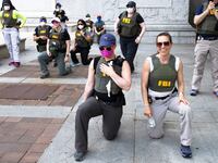 Federal Bureau of Investigation (FBI) officers take a knee with demonstrators, as they march on Pennsylvania Av. Thursday, June 4, 2020, in Washington, during a protest over the death of George Floyd, an unarmed black man, who died after a police officer kneeled on his neck for several minutes.