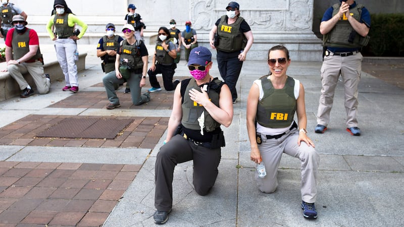 Federal Bureau of Investigation (FBI) officers take a knee with demonstrators, as they march on Pennsylvania Av. Thursday, June 4, 2020, in Washington, during a protest over the death of George Floyd, an unarmed black man, who died after a police officer kneeled on his neck for several minutes.