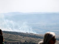 People watch as smoke rises at the site of a rocket strike from Lebanon on the Israel-annexed Golan Heights on May 17, 2024, amid ongoing cross-border clashes between Israeli troops and Hezbollah fighters.