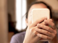 Young girl holding smartphone up to face.