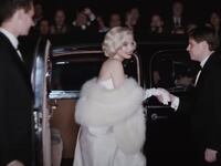 A woman in a fur coat is helped out of a limousine.