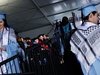Students from the Columbia School of Professional Studies wear keffiyehs and celebrate after walking the stage during the schools graduation ceremony.