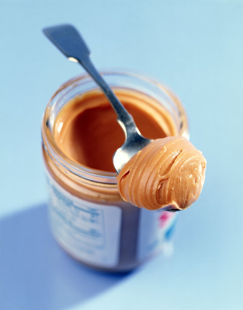 a jar of peanut butter with a spoonful resting on top of the jar's rim