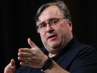 Reid Hoffman speaking on stage at an event.