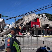 TOPSHOT - Police gather in front of a collapsed Jollibee fast food restaurant after an 7.8 magnitude earthquake in General Santos City on June 8, 2026. A 7.8-magnitude earthquake that struck the southern Philippines on June 8 killed at least one person and collapsed buildings, police said, as the disaster sparked tsunami warnings across the region. (Photo by Edwin Espejo / AFP via Getty Images)