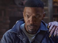 A man stands with an undead hand on his shoulder.