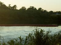 An unfinished strand of orange buoys sits in the Rio Grande River in response to migrants crossing the river, near Eagle Pass, Texas.