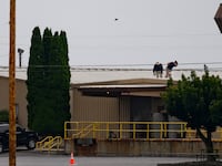 Two FBI investigators scan the roof of AGR International Inc, the building adjacent to the Butler Fairgrounds, from which alleged shooter Matthew Thomas Crooks fired at former President Donald J. Trump