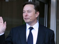 Elon Musk waves his hand.