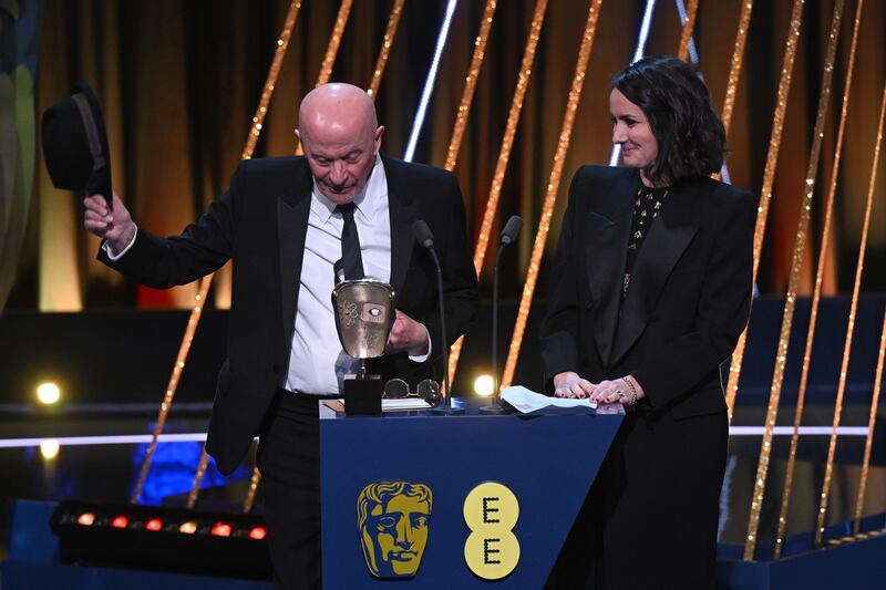 Jacques Audiard (L) accepts the Film Not in the English Language Award for 'Emilia Pérez' on stage during the EE BAFTA Film Awards 2025 at The Royal Festival Hall on February 16, 2025 in London, England.