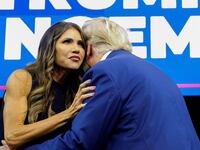 A photo of Kristi Noem embracing Donald Trump onstage at a rally.