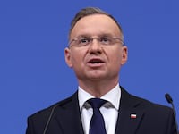 Polish President Andrzej Duda speaks before a blue background.