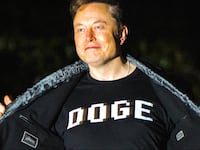 Elon Musk opens his jacket to show his shirt that says “DOGE” as he walks into the White House after landing in Marine One on the South Lawn.