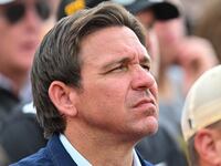 Ron DeSantis stares forward in the stands at a college football game.