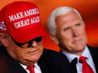 Donald Trump exits a stage with his head down with Mike Pence behind him.