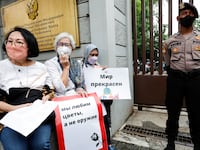 Activists carrying placards sit as a police officer guards outside the Russian Embassy during a protest calling for peace and stopping the war, following Russia’s ongoing invasion of Ukraine, in Jakarta, Indonesia, March 30, 2022.
