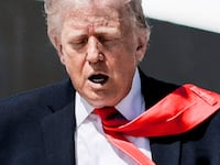 U.S. President Donald Trump's tie is blown by the wind as he walks to board Air Force One .