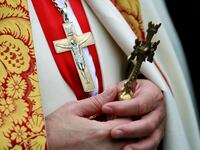 A priest holds a cross.