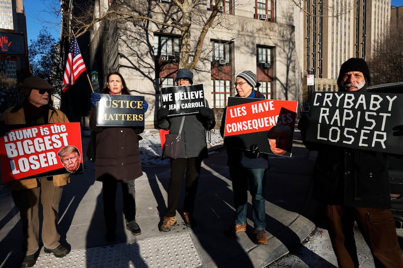 NEW YORK, NEW YORK - JANUARY 22: Protestors hold up signs outside of Manhattan Federal Court before the start of the E. Jean Carroll civil defamation trial against former President Donald Trump on January 22, 2024 in New York City. Former President Trump is scheduled to testify in his civil defamation trial on the eve of the New Hampshire primary. A verdict is expected this week in the trial that will decide how much money in damages the former president will have to pay Carroll for his 2019 defamatory statements about her sexual assault allegations. (Photo by Michael M. Santiago/Getty Images)